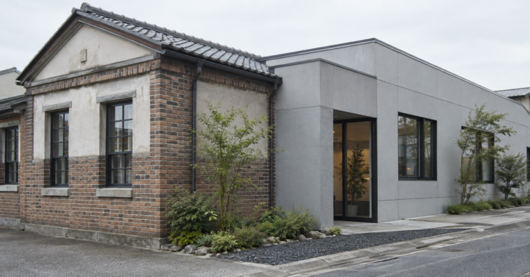 レンガ造りの建物と、新しいグレーの増築部分がつながる外観
